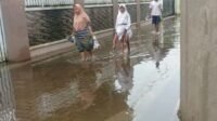 Nampak warga berjalan melewati genangan air