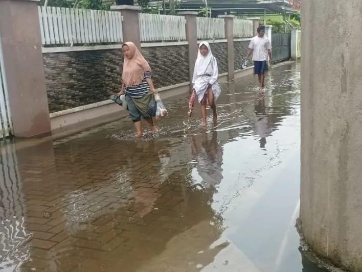 Nampak warga berjalan melewati genangan air